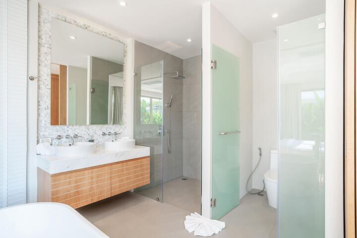 Frameless bathroom mirror beside a glass shower with a frosted panel